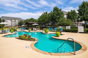a swimming pool with chairs and umbrellas in front of a building